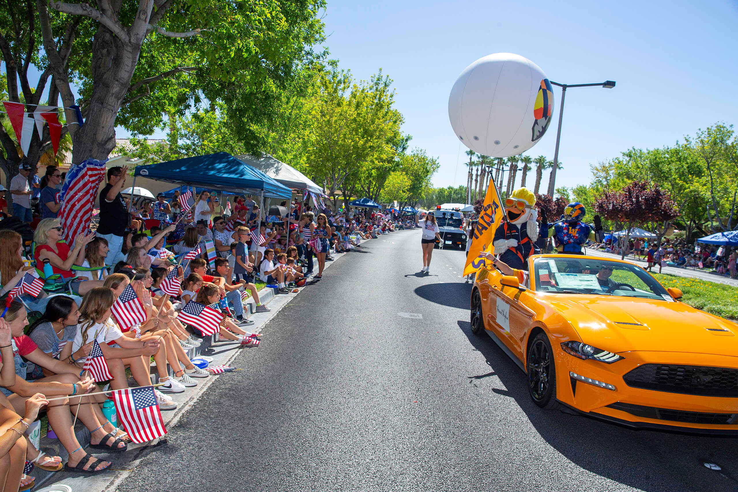 Parade participants queue up on bicycles behind a stilt-walker dressed as Uncle Sam